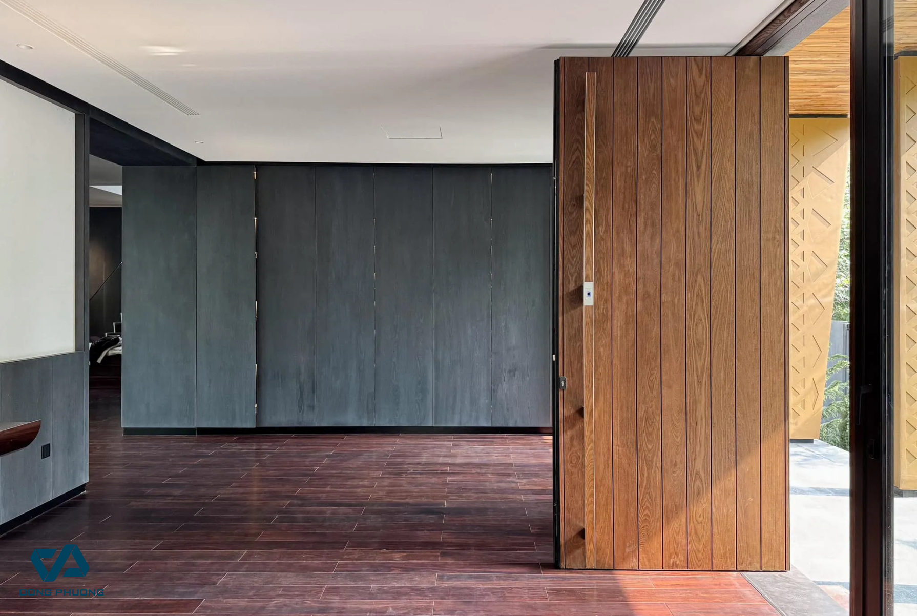 Cửa pivot Aluman thiết kế nguyên tấm, kết cấu vững chắc, chuyển động xoay mượt mà. Vân gỗ tự nhiên mang lại sự hài hòa hoàn hảo với nội thất hiện đại bên trong biệt thự.