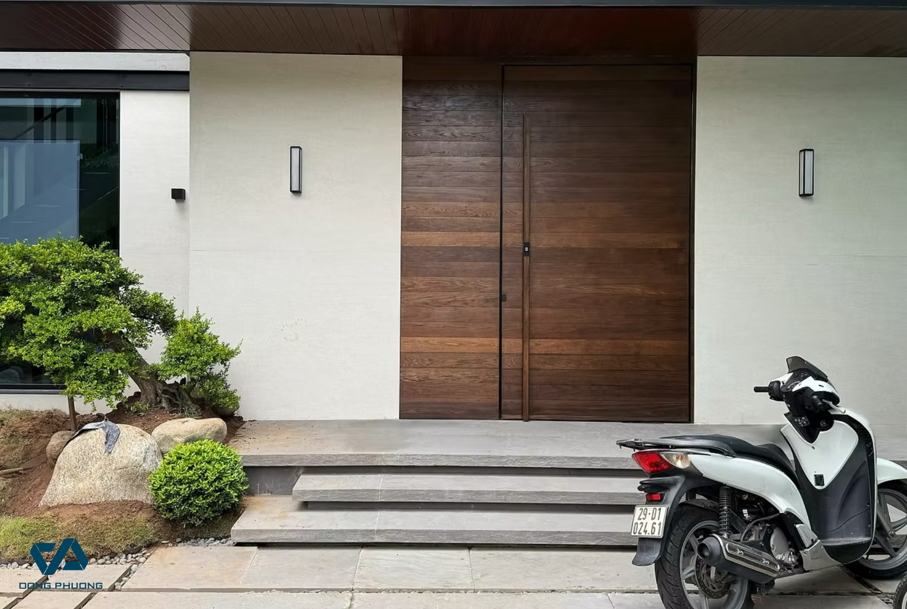 Mẫu cửa Aluman vân gỗ cao cấp mang lại vẻ ấm cúng nhưng vẫn giữ nét đẳng cấp cho mặt tiền biệt thự. Tay nắm chạy dọc liền mạch tạo hiệu ứng thẩm mỹ mạnh mẽ và hiện đại.